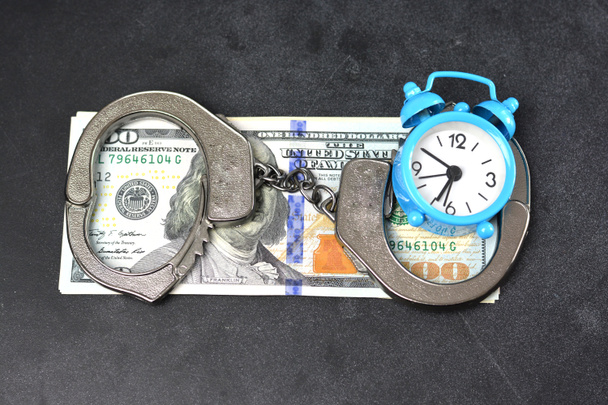 Handboeien, geld en wekker op donkere achtergrond, borgtocht concept - Foto, afbeelding