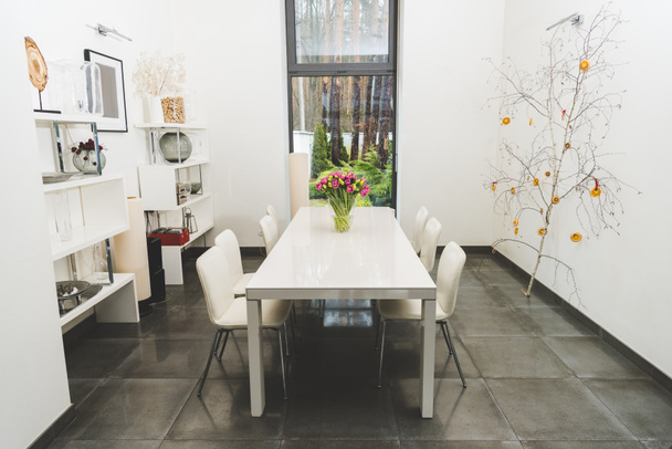 weergave van stijlvolle lege eetzaal met boeket tulpen op tafel - Foto, afbeelding