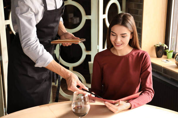 Cameriere aiutare la giovane donna a fare ordine al ristorante
 - Foto, immagini