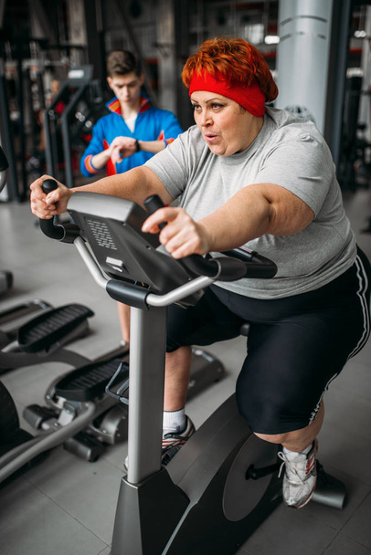 mujer con sobrepeso, entrenamiento en bicicleta estática en el gimnasio
 - Foto, Imagen