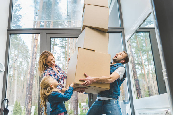 happy family holding cardboard boxes together at new home, moving home concept - Photo, Image