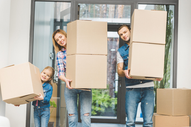 Семья, держащая картонные коробки в новом доме, концепция переезда домой
 - Фото, изображение