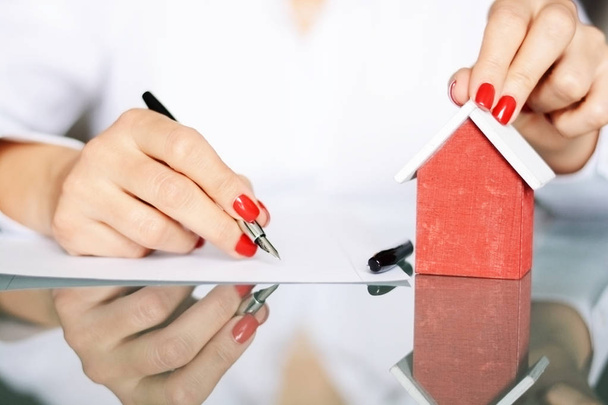 Mulher assinando um contrato ao comprar uma nova casa com empréstimo hipotecário
 - Foto, Imagem