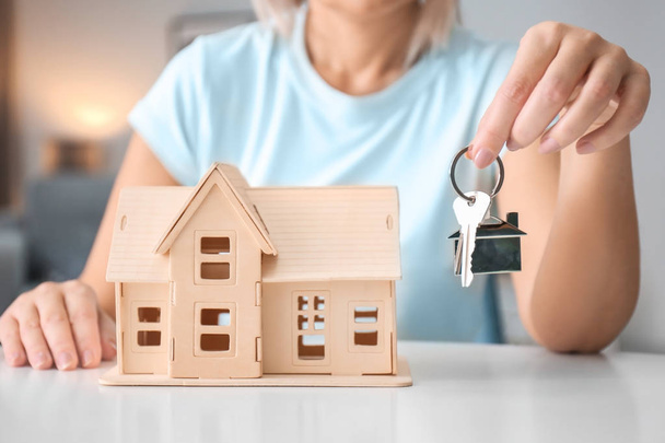 Woman holding key near house model, closeup - Foto, Imagem