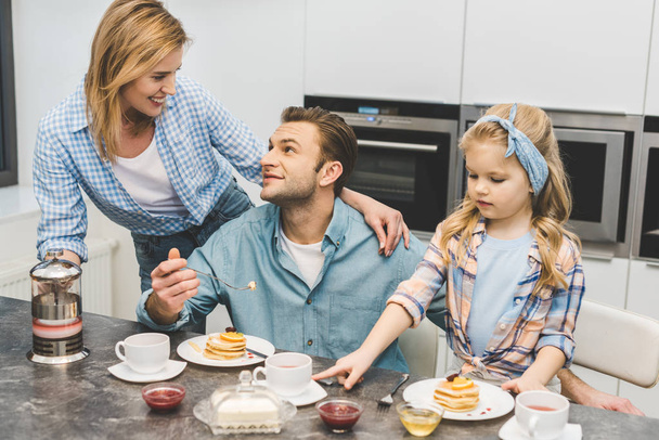 parents and little daughter having breakfast together at home - Photo, image