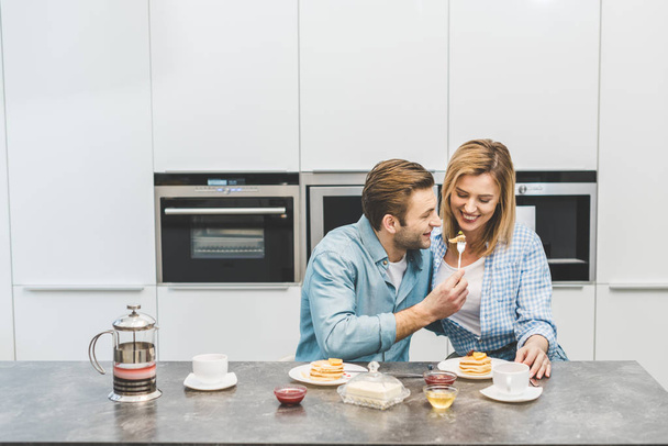 portrait of couple having breakfast together in kitchen at home - Фото, изображение