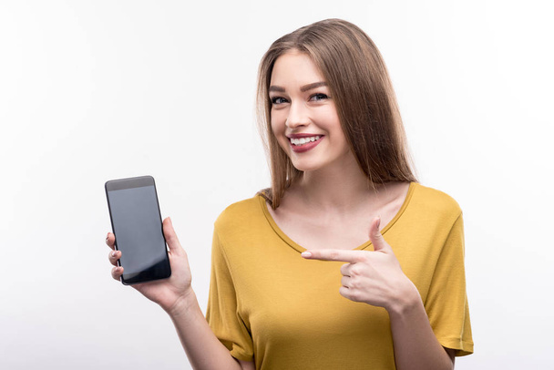 Cute young woman pointing at her mobile phone - Foto, Bild