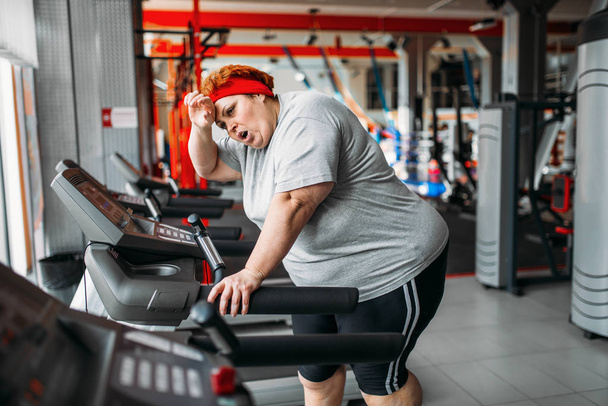 fat tired woman running  on treadmill after running in gym - Photo, Image