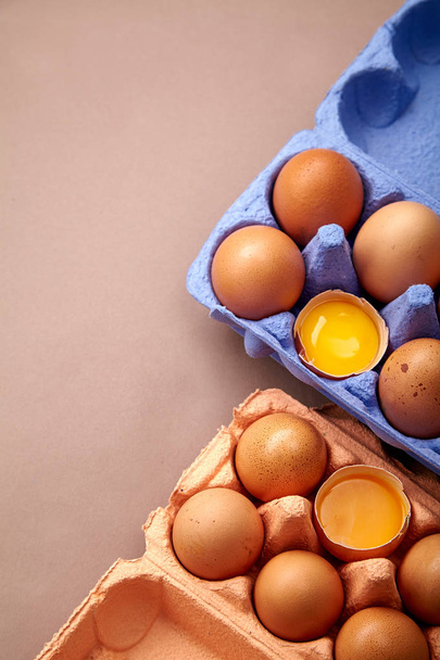 close-up with two colorful cardboard containers of pink and violet color with yolks and chicken eggs  - Foto, afbeelding