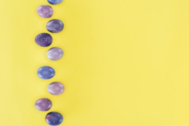 vista superior de huevos de Pascua pintados de púrpura, aislados sobre fondo amarillo
 - Foto, imagen