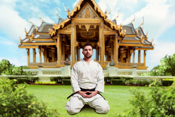 bojovník v bílém kimonu meditoval v józe pozice poblíž kláštera  - Fotografie, Obrázek