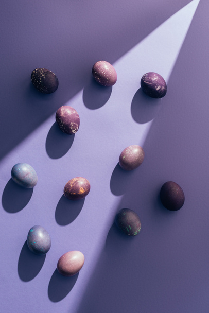 Easter purple eggs on purple background with sunbeam - Photo, Image