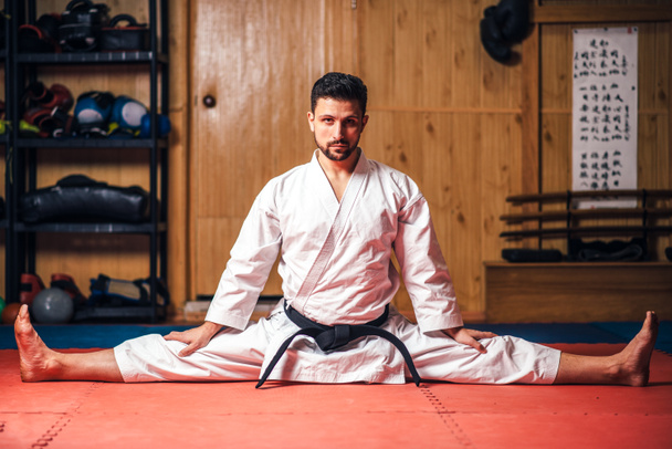 fehér kimonó fekete öv nyújtási gyakorlat, karate, képzés az edzőteremben csinál harcos - Fotó, kép