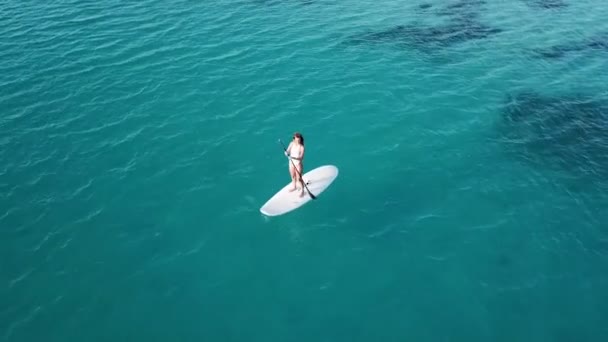 Luchtfoto van jong meisje opkomen peddelen op vakantie. Tracking shot van een jonge vrouw Sup instappen - Video