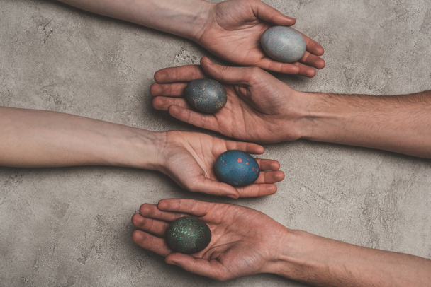 cropped view of hands with shabby easter eggs on concrete surface  - Zdjęcie, obraz