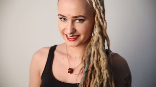 moderne jeugd. Portret van een vrolijke mooi meisje van ongewone verschijning - dreadlocks, piercings en tatoeages. - Video