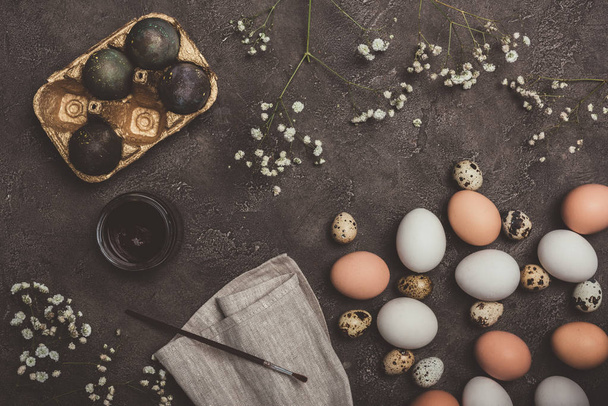 vue du dessus des œufs peints en plateau doré, oeufs de caille et de poulet, peinture et brosse sur tissu et surface en béton, décorations de Pâques
  - Photo, image