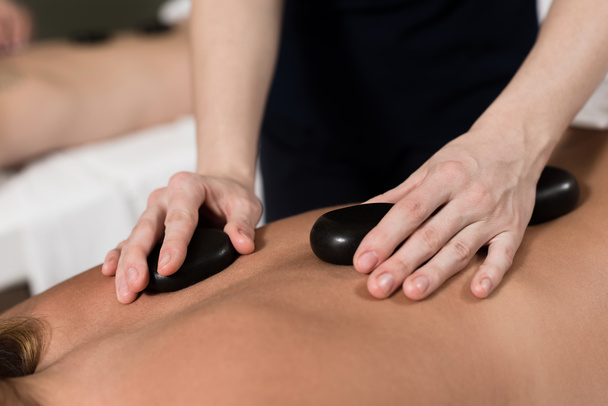 ritagliato colpo di donna con pietre calde massaggio nel salone spa
 - Foto, immagini