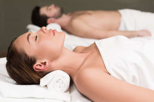 side view of couple with closed eyes lying in spa center - Фото, изображение