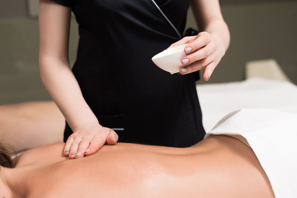 abgeschnittene Aufnahme einer Frau beim Entspannen und bei einer Körpermassage im Wellness-Salon - Foto, Bild