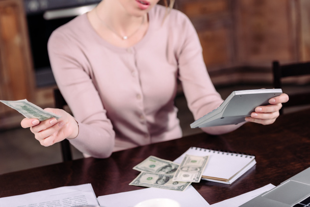 обрізаний знімок жінки, що рахує гроші за столом вдома
 - Фото, зображення
