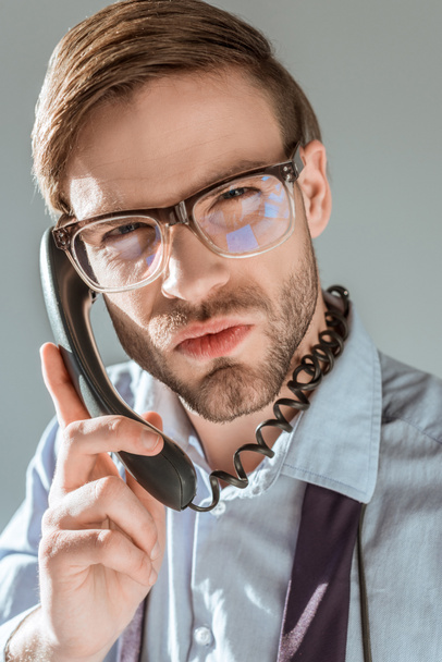 Close-up view of dissatisfied businessman talking on the phone isolated on grey - Photo, Image
