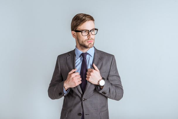 Giovane uomo d'affari sicuro in giacca e cravatta isolato su grigio
 - Foto, immagini