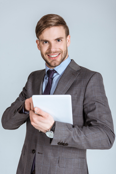 Молодий впевнений бізнесмен, використовуючи цифровий планшет ізольований на сірому
 - Фото, зображення