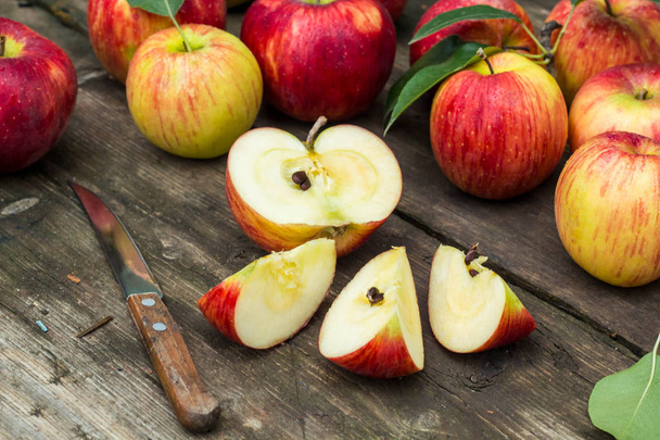 Червоне яблуко нарізане і ніж на старому дерев'яному столі
 - Фото, зображення
