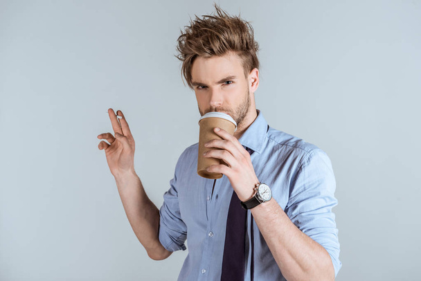 Homme d'affaires fatigué tenant la cigarette et buvant dans une tasse en papier isolée sur gris
  - Photo, image