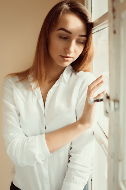 Closeup shot of lovely brunette lady in white shirt standing at  - 写真・画像