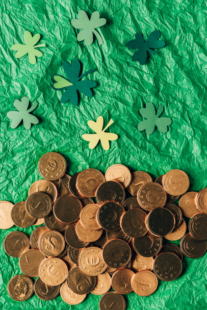 top view of golden coins and paper shamrock on green surface, st patricks day concept - Foto, afbeelding