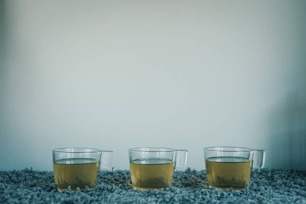 Three cups of green tea in line with a teapot - Photo, Image