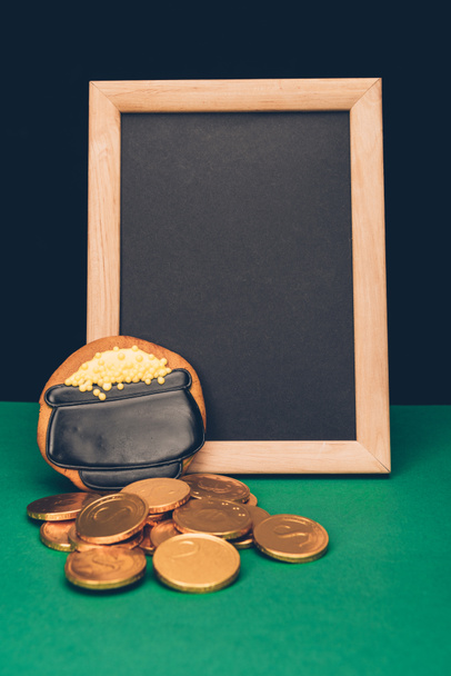 empty board with golden coins and gingerbread on green table, st patricks day concept - Foto, Imagen