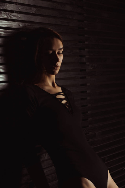 Senhora morena macia em lingerie preta posando perto da parede de madeira
 - Foto, Imagem
