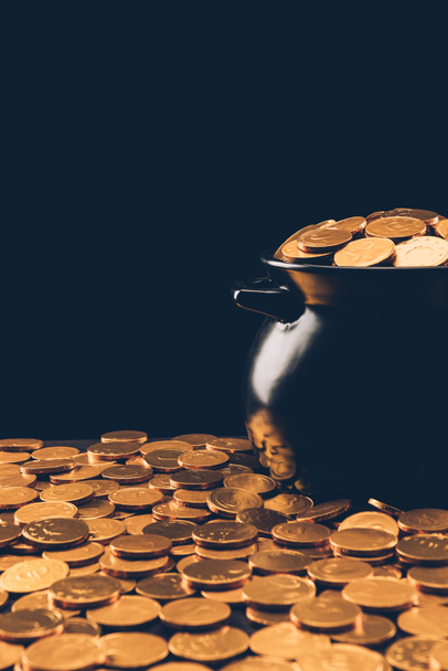 schwarzer Topf mit goldglänzenden Münzen isoliert auf schwarzem, st patricks day concept - Foto, Bild
