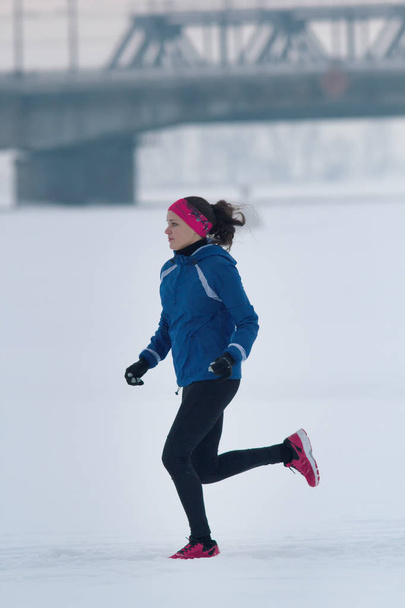 Giovane atleta donna che corre diligentemente in inverno attraverso la neve
 - Foto, immagini