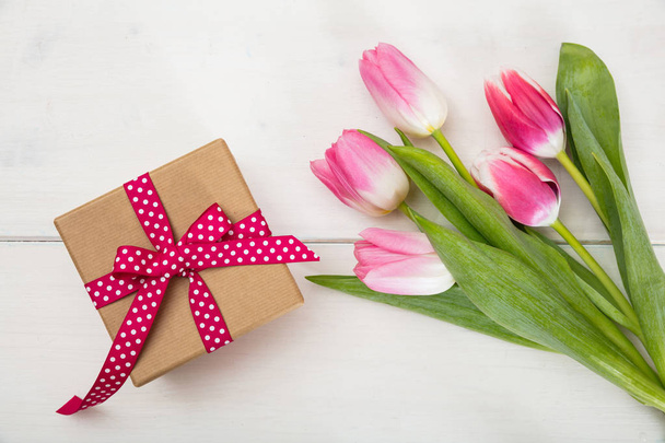 Женский день. Розовые тюльпаны и подарок на белом фоне, вид сверху
 - Фото, изображение