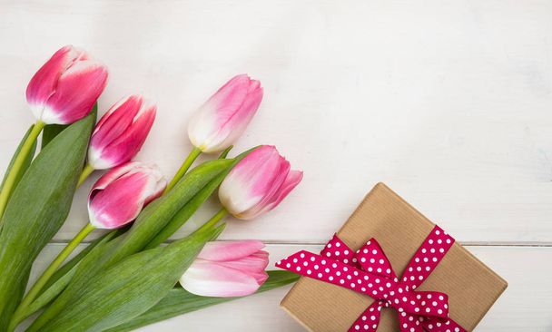 Women's day. Pink tulips and a gift on white background, top view - Foto, afbeelding