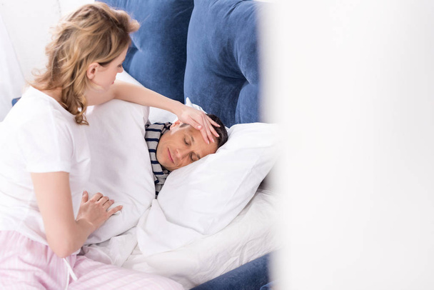 Kontrola teploty nemocného manžela v posteli doma žena - Fotografie, Obrázek