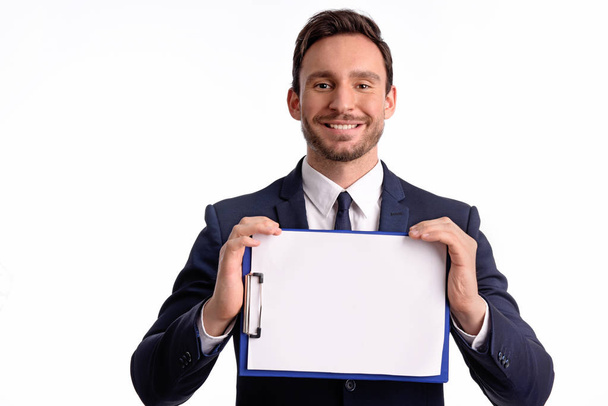 Handsome bearded businessman in office suit and tie isolated on white background. Professional bank manager is holding a blank clipboard - Φωτογραφία, εικόνα