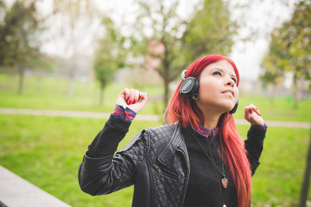 retrato jovem ruiva mulher venezuelana ouvir música olhando para longe com fones de ouvido espalhando braços
 - Foto, Imagem