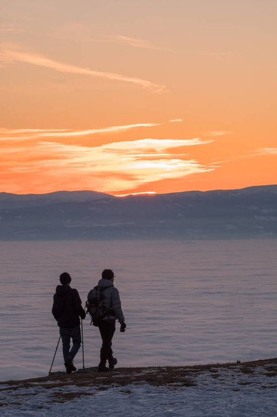 日没までの低層雲の山に歩いて 2 つのハイカー - 写真・画像