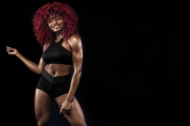 Sporty bella afro-americana modello, donna in abbigliamento sportivo rende fitness esercizio su sfondo nero per rimanere in forma
 - Foto, immagini
