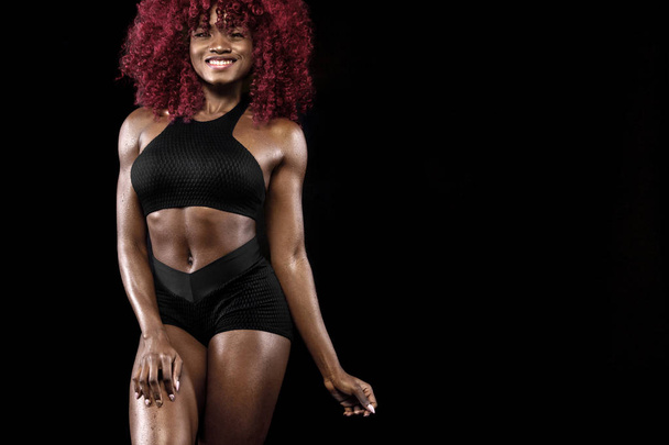 Sporty beautiful afro-american model, woman in sportwear makes fitness exercising at black background to stay fit - Fotoğraf, Görsel