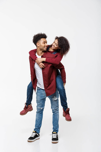 Full length young attractive african american lady riding back on her boyfriend back and enjoy playing to each other. - Photo, image