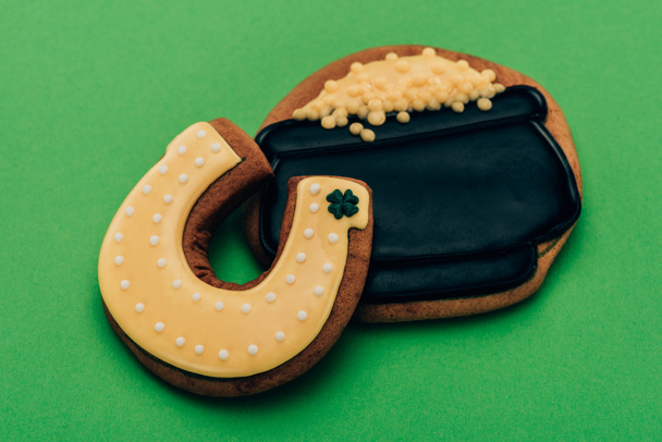 high angle view of icing cookies in shape of horseshoe and pot with coins on green, st patricks day concept - Photo, Image