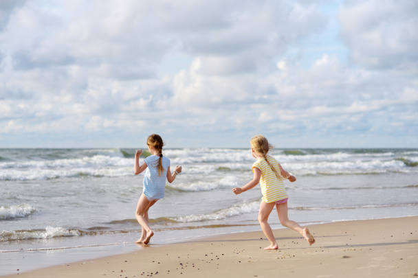 Kaksi pikkusiskoa pitää hauskaa hiekkarannalla lämpimänä ja aurinkoisena kesäpäivänä. Lapset leikkivät meren rannalla. Kesätoimintaa lapsille
. - Valokuva, kuva