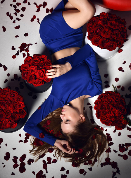 woman lying on red lips sofa couch in blue dress smiling with roses bouquet flowers petals - Photo, image