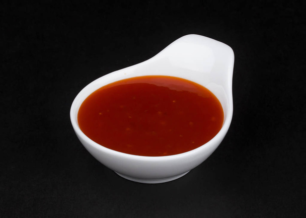 Hot chilli sauce in white bowl isolated on black background - Photo, Image